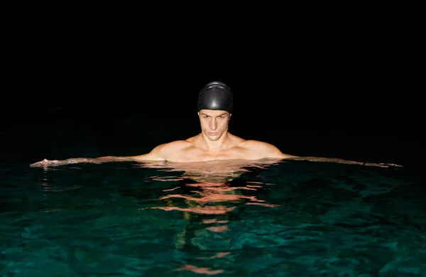 Homem se preparando para o treinamento de natação em uma piscina à noite . — Fotografia de Stock