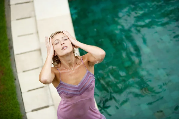 Mujer junto a una piscina bajo la lluvia en el verano . — Foto de Stock