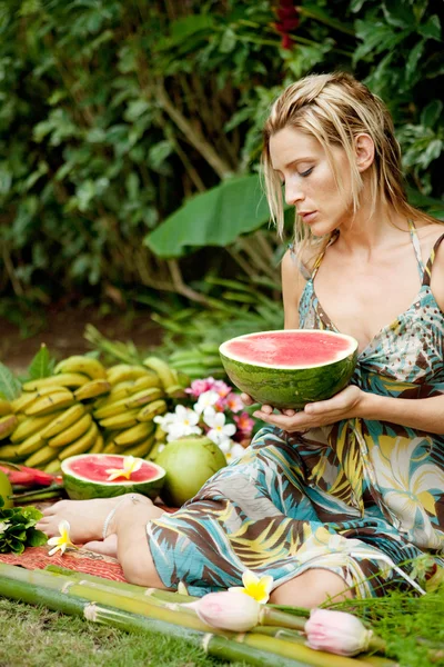 Jonge aantrekkelijke vrouw omgeven door tropische vruchten in een exotische tuin. — Stockfoto