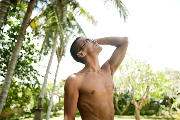 Atractivo joven inclinado hacia atrás y disfrutando de la naturaleza mientras está de vacaciones en un destino tropical . —  Fotos de Stock