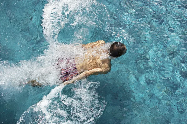 Vista sobre la cabeza de un hombre sumergiéndose en una piscina, salpicando en el agua . — Foto de Stock