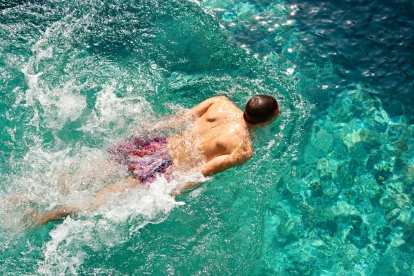 顶上后视图的一名年轻男子游泳下在度假时的蓝色游泳池中的水. — 图库照片
