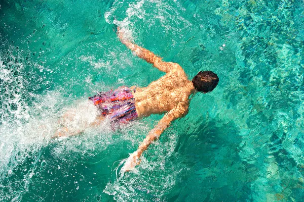 tatil sırasında bir mavi yüzme havuzunda su altında yüzmek genç bir adam görünümü üzerinde başını arka.