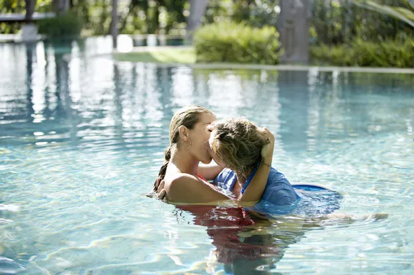 Coppia immerso in una piscina, baci e abbracci mentre vestito . — Foto Stock