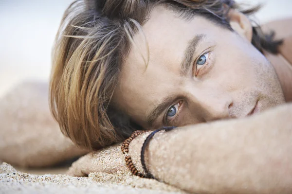 Attractive young man laying down on a white sand beach. — Stock Image Attractive young man laying down on a white sand beach. Royalty Free Stock Photos
