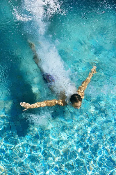 Hombre sumergiéndose en una piscina, formando una forma de flecha y dejando un rastro detrás de él . Imagen de archivo
