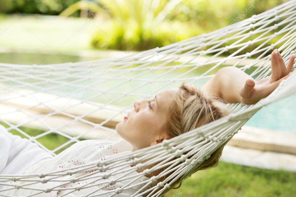 young woman laying down and relaxing on a white hammock