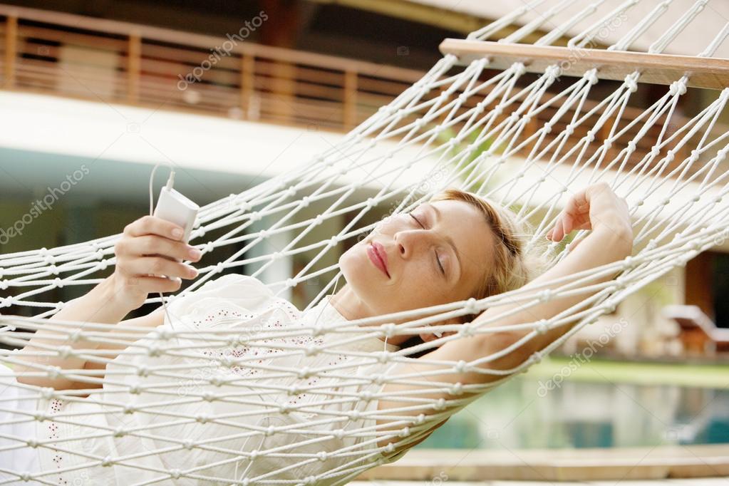 Attractive young woman laying down and relaxing on a white hammock