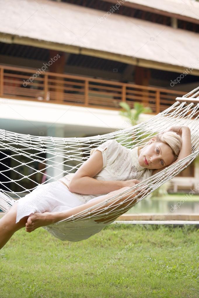 young woman listening to music while sitting on a hammock