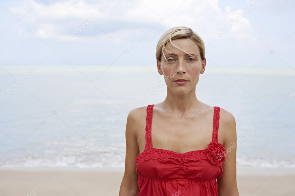 Portrait of an attractive blonde woman standing by the sea.