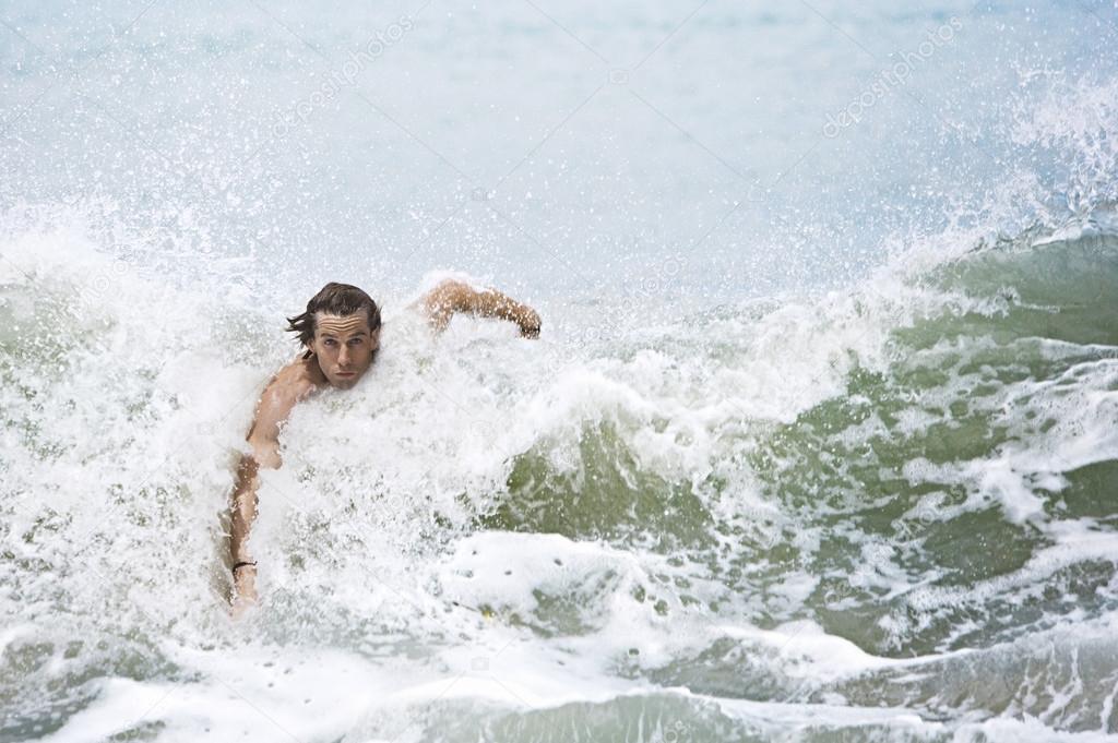 Young man swimming large ocean waves.