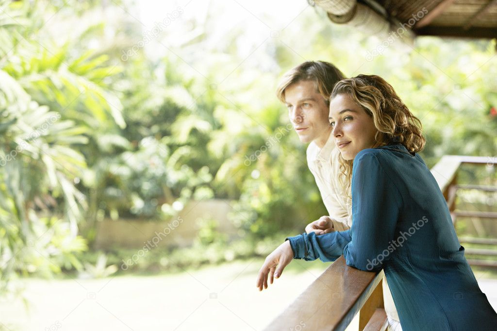 young couple on vacations, leaning on a balcony's veranda