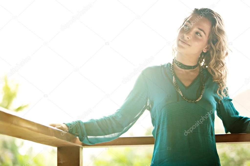 Young attractive woman leaning on a tropical garden balcony