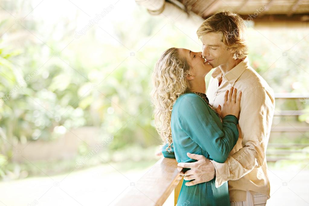 Young couple kissing on a tropical home's balcony
