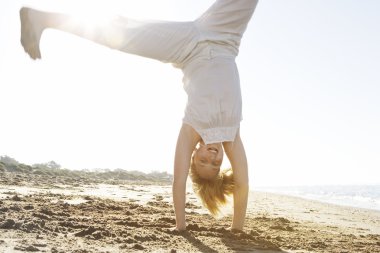 Cartwheels altın güneş ışığı ile bir plajda yaparken kız.