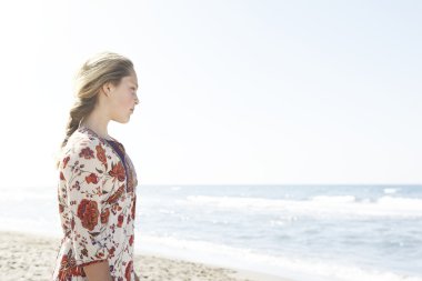 plaj kıyısında dururken, denize bakan kız.