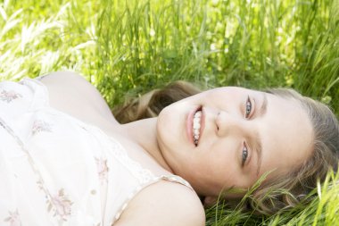 uzun yeşil çimlere bırakmasını ve kameraya gülümseyen kız onun ev bahçesinde portresi.