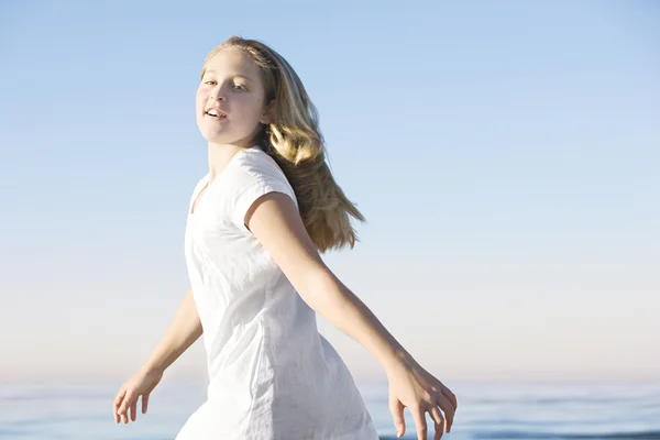 Meisje wandelen langs het strand met de horizon en een blauwe hemel in de achtergrond. — Stockfoto