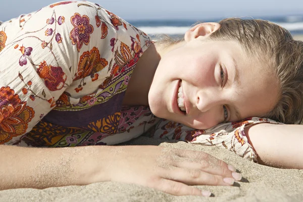 Close up retrato de uma menina deitada em uma praia de areia dourada . — Fotografia de Stock