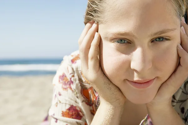 Close up portrait of a girl laying down on a golden sand beach, smiling. — Stock Photo, Image