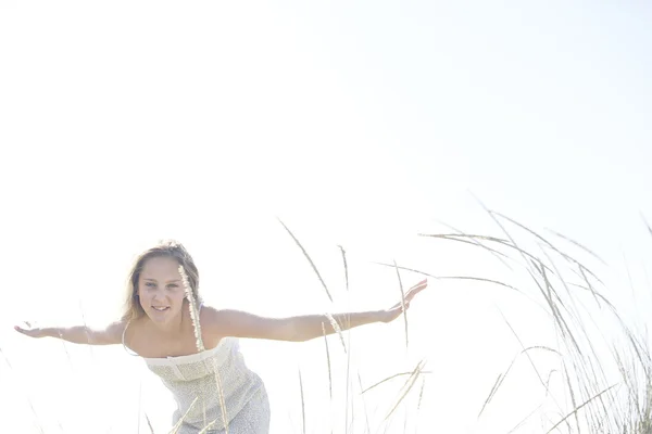 Menina com os braços estendidos, brincando como um avião e sorrindo contra o céu aberto . — Fotografia de Stock