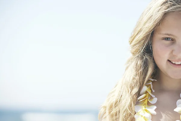 De helft van een meisje gezicht lachend op het strand, met een blauwe lucht op de achtergrond. — Stockfoto