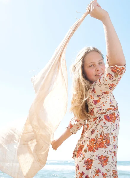 Mladá dospívající dívka drží sarong v vzduchu ve větru proti modré obloze, usmíval se. — Stock fotografie