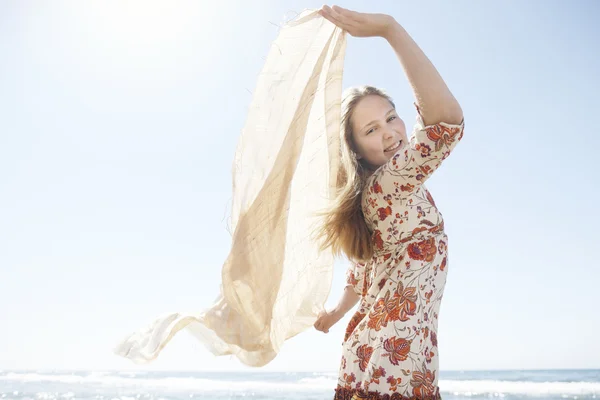 Girl holding a floating sarong in the air, smiling at the camera. — Stock Photo, Image