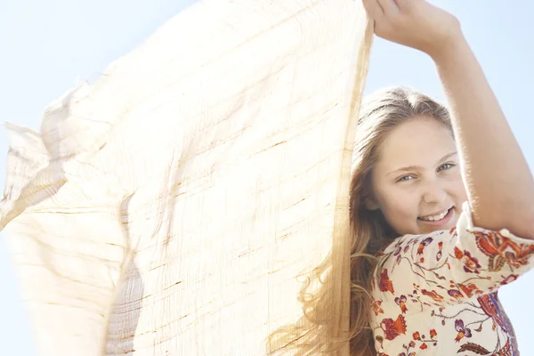 Close up view of a girl holding fabric in the air and smiling at the camera. — Stock Photo, Image