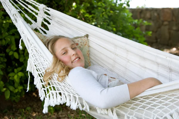 Porträt eines jungen Teenagermädchens, das sich in einem Garten auf eine Hängematte legt und entspannt — Stockfoto