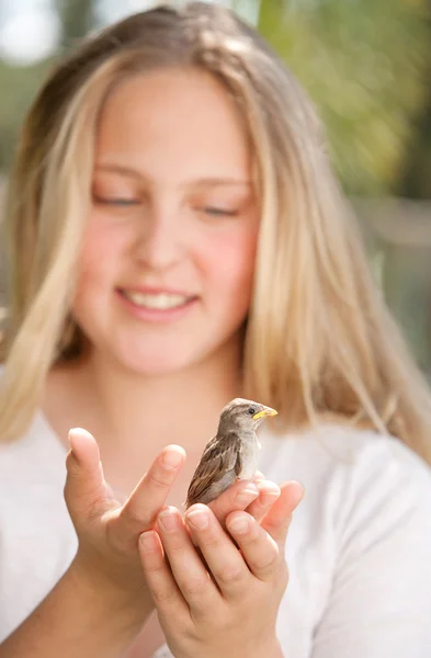 Close up portrait of a young teenage girl holding a baby bird in her hands, smiling. — Stock Photo, Image
