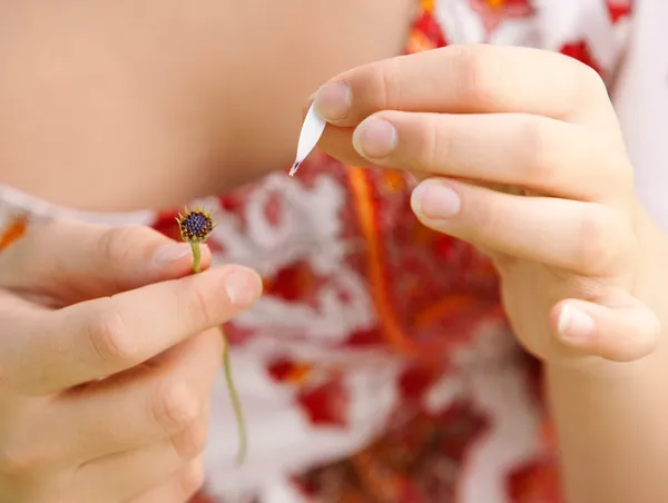 Joven adolescente tirando pétalos de una flor de margarita, jugando a amarme no me ames — Foto de Stock