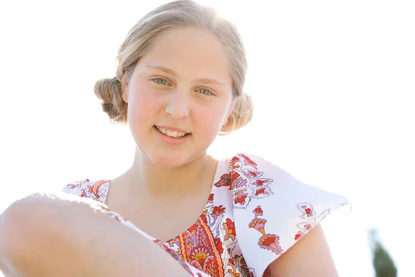Portret van een tienermeisje glimlachend tegen een zonnige hemel close-up. — Stockfoto