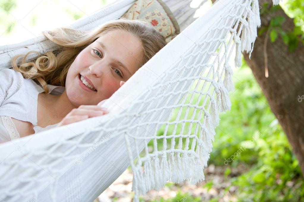 young teenage girl laying down on a hammock in a garden