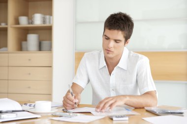 genç adam mutfakta onun ev maliyesi üzerinde çalışma.