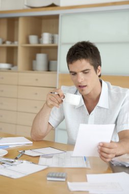 genç adam mutfakta onun ev maliyesi üzerinde çalışma.