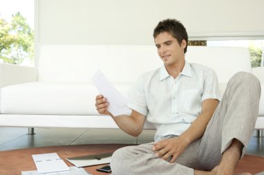 genç adam yere tarafından kanepe oturma onun maliyesi üzerinde çalışma.