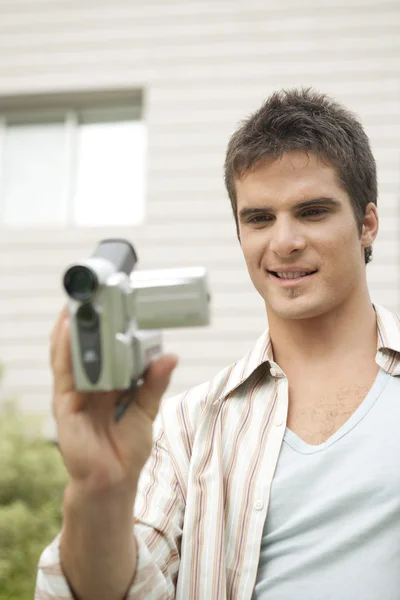 Junger Mann mit digitaler Videokamera im Bürogarten. — Stockfoto
