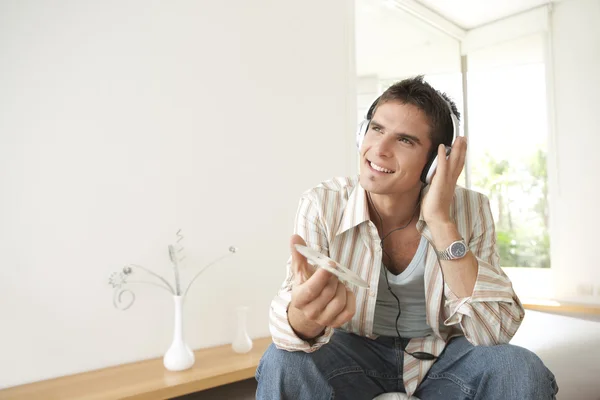 Hombre escuchando música en casa, usando auriculares — Foto de Stock