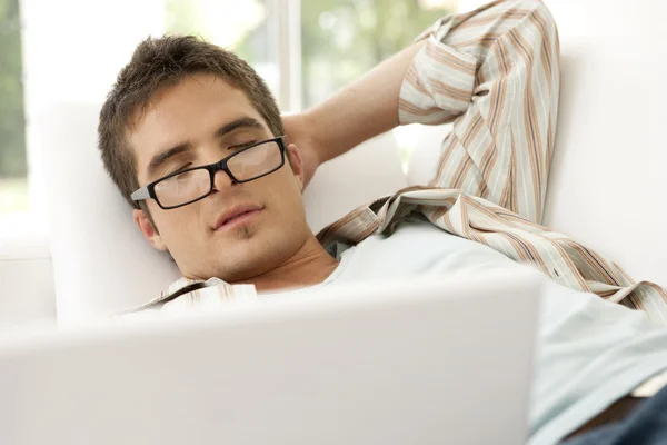 Retrato de homem adormeceu no sofá enquanto usava um computador portátil . — Fotografia de Stock