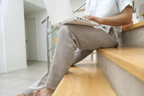 Joven profesional usando un portátil mientras está sentado en una escalera moderna . —  Fotos de Stock