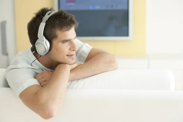 Mladý muž poslouchá hudbu se sluchátky doma. — Stock fotografie