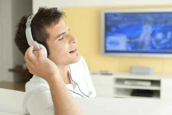 Jeune homme écoutant de la musique avec écouteurs à la maison . — Photo