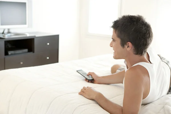 Joven profesional usando un mando a distancia en una habitación de hotel . —  Fotos de Stock