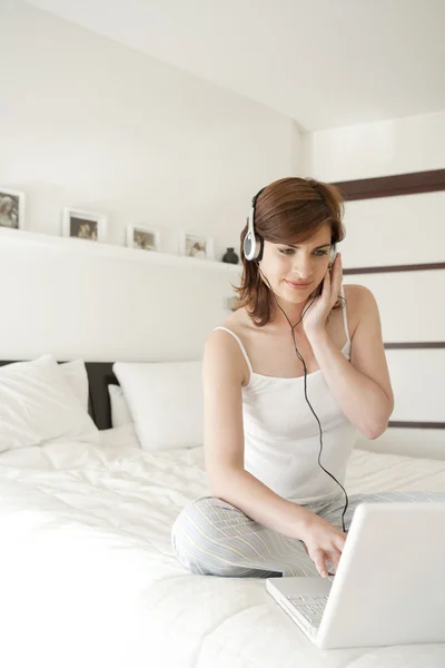 Jonge vrouw luisteren naar muziek in bed — Stockfoto