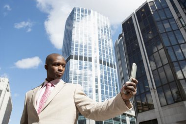 Finans Merkezi duran bir cep telefonu kullanarak iş adamı.