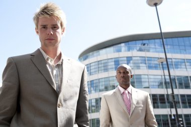 Two businessmen standing by a modern office building.