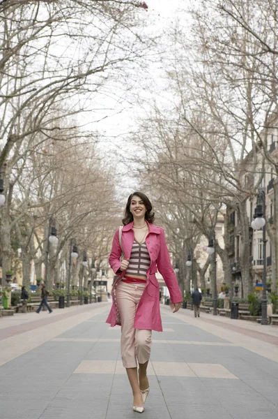 Jovem mulher na moda andando por uma rua pedonal . — Fotografia de Stock