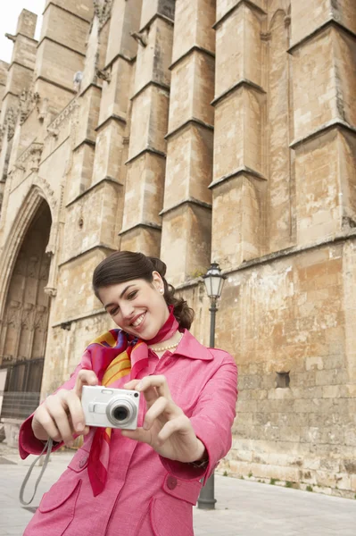Elegante joven turista tomando fotos cerca de un monumento . —  Fotos de Stock