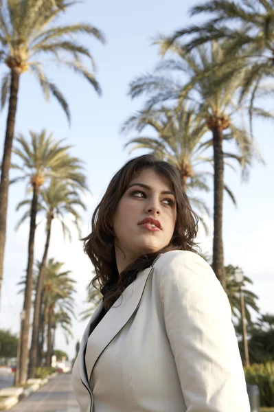 Retrato de una mujer joven dando vueltas en una calle alineada con un árbol . — Foto de Stock